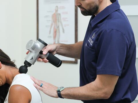 Percussion therapy on a patient's shoulder at Vertebre Chiropractic Studio
