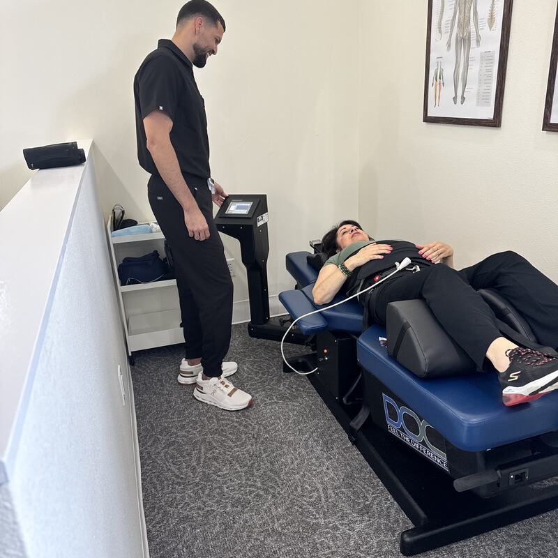 Dr. Nandy Toro at the decompression table console while a patient is treated at Vertebre Chiropractic Studio